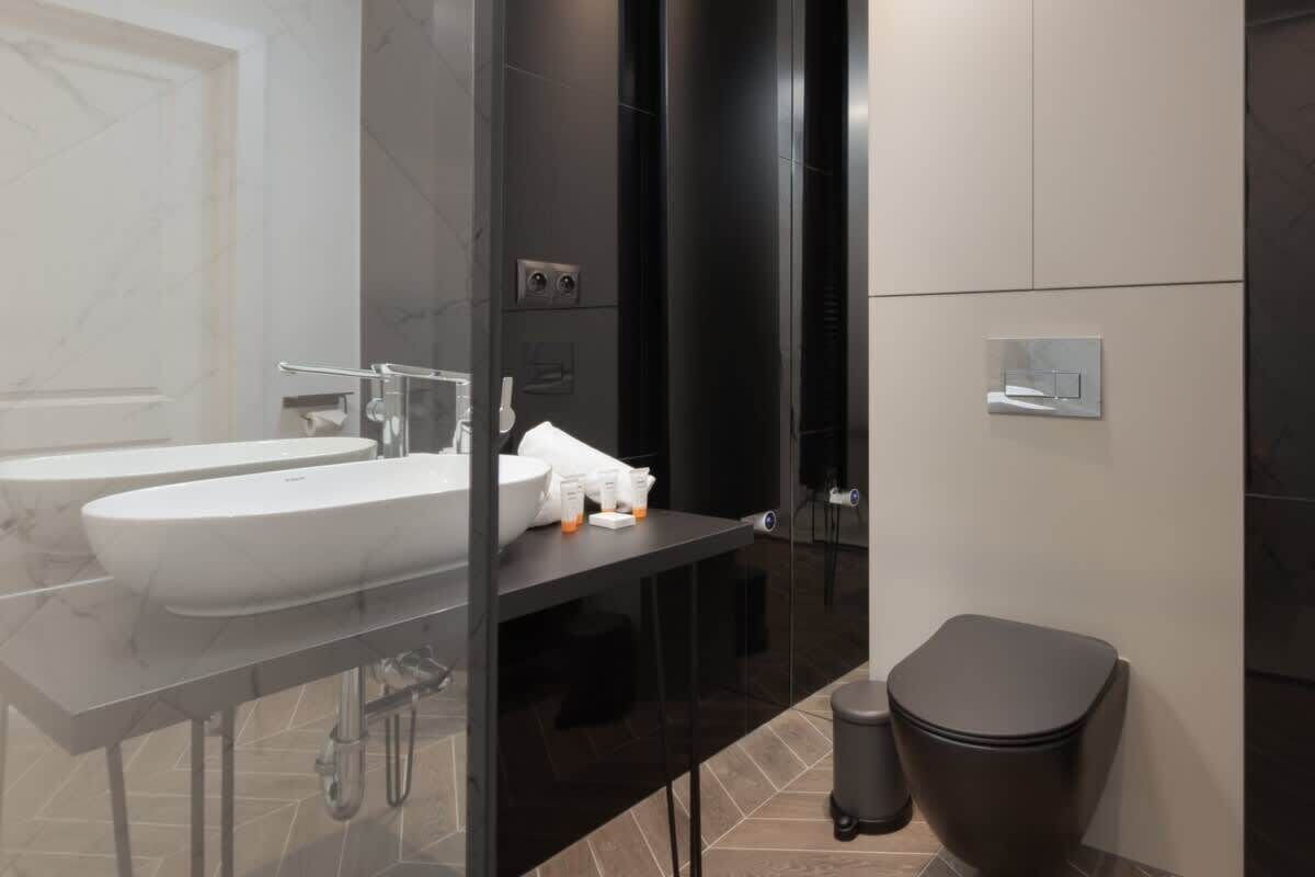 A modern bathroom with a dual sink vanity, a toilet, and a glass-enclosed shower area.