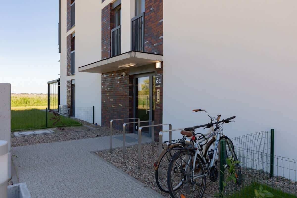 Un bâtiment moderne avec une façade en briques et un balcon. On peut voir des vélos garés à l’extérieur.