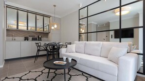 Ein modernes Wohnzimmer mit einem weißen Sofa, einem runden Couchtisch und einem Essbereich mit Stühlen und einem Tisch.
