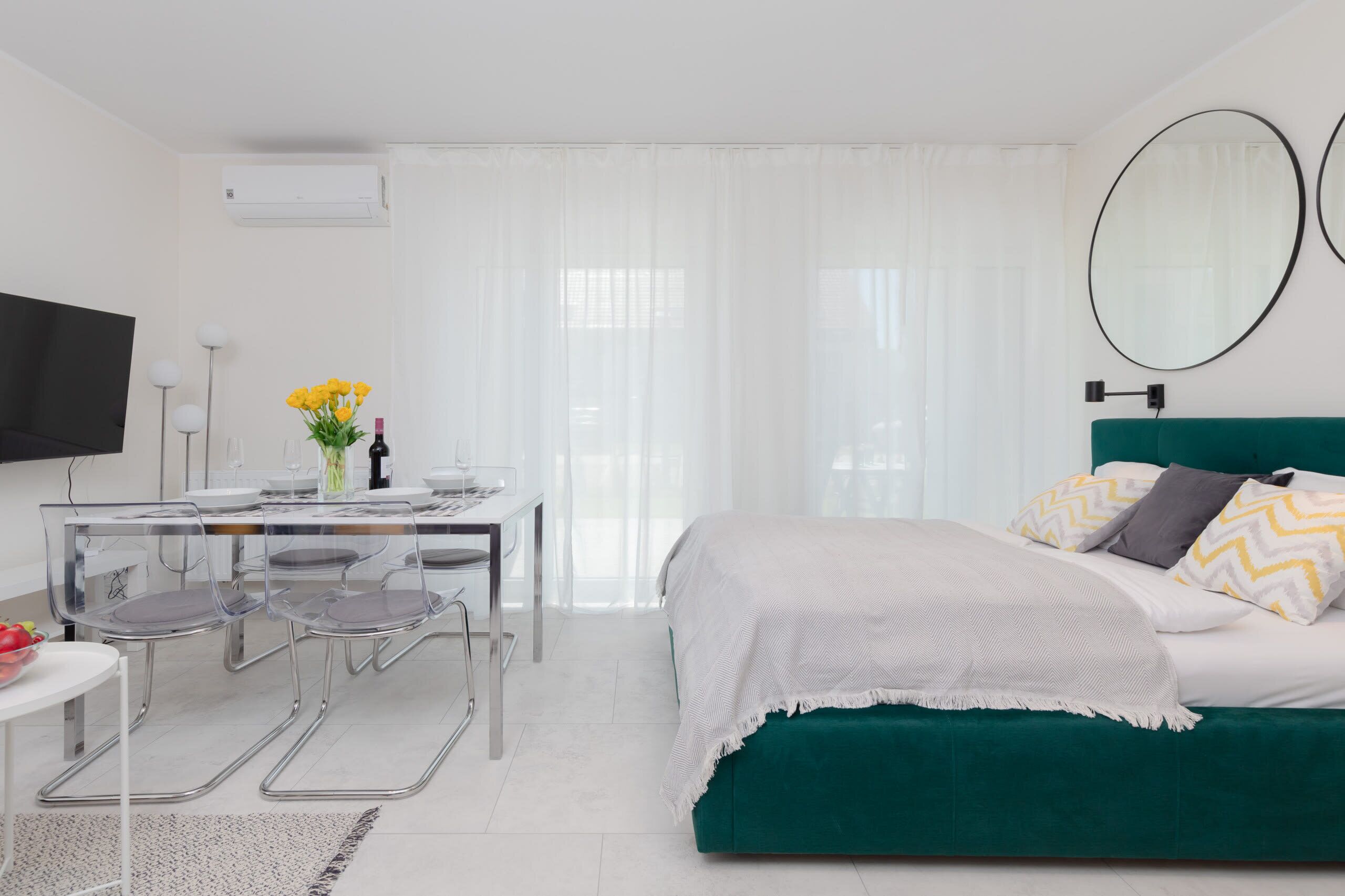 A modern hotel room with a bed, a desk, and chairs.