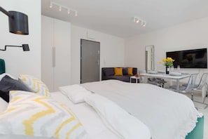 Ein modernes Hotelzimmer mit einem großen Bett, einem Schreibtisch mit Stuhl, einem Flachbildfernseher und einer Tür.