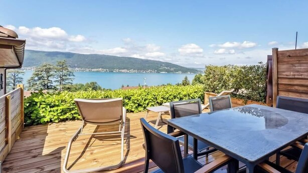 A wooden deck with a glass-top table and chairs, overlooking a lake and mountains. - Apartment with 180° Lake & Mountain Views (Veyrier-du-Lac)