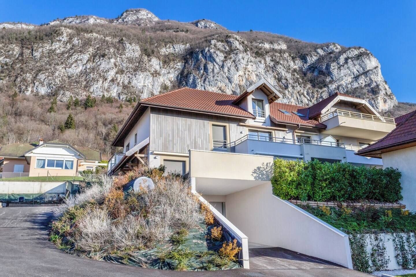 Une maison moderne avec un toit en pente, un escalier menant à l’entrée et une vue sur un paysage montagneux.