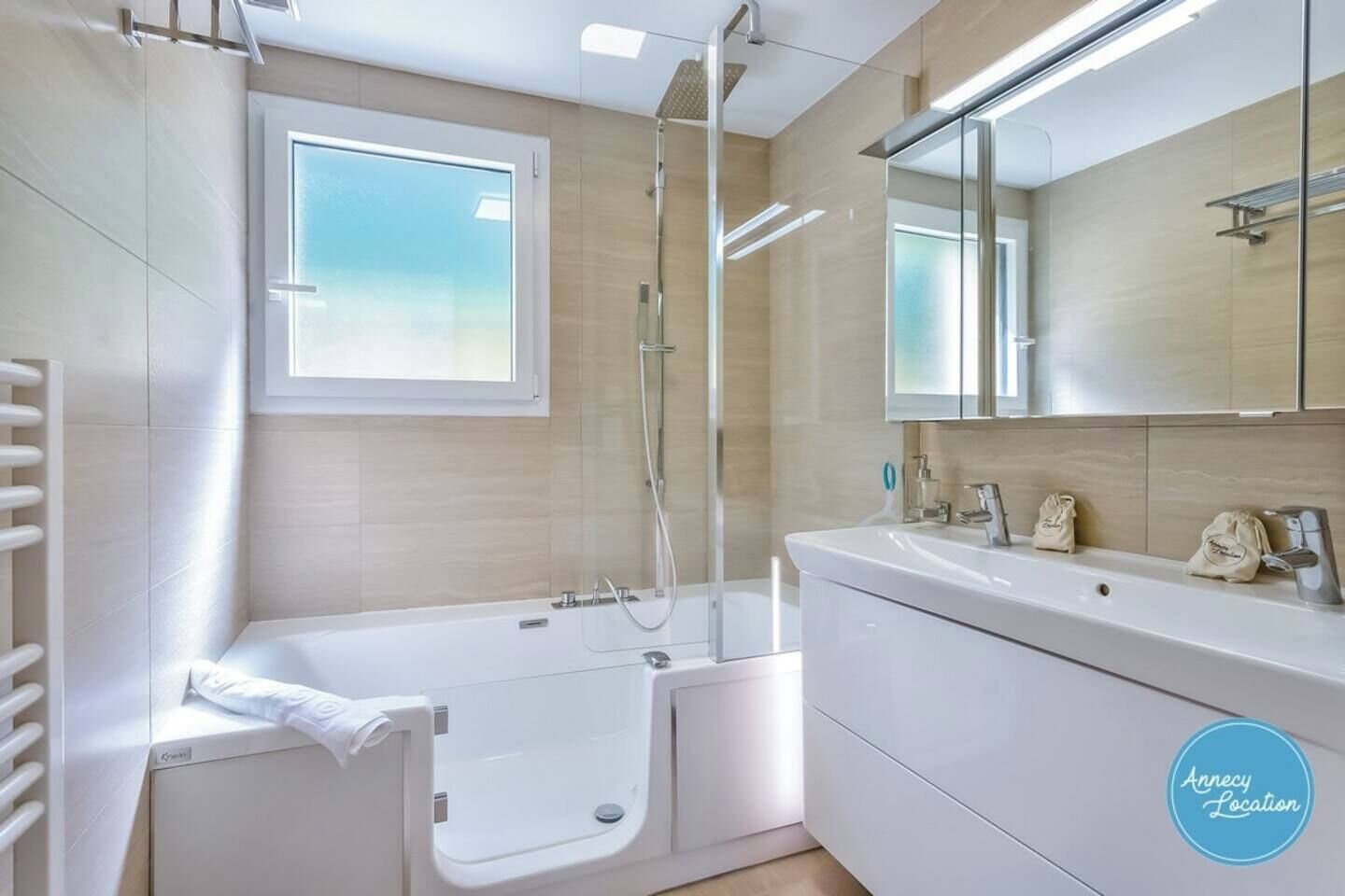 Une salle de bain moderne avec une baignoire, une douche, un grand miroir et une fenêtre.