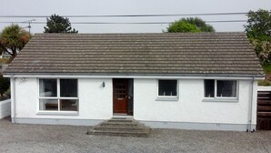 A single-story building with a sloped roof, a front door, and a small porch. - 3 Bed Bungalow - Sleeps 6 - Pet Friendly - Parking (Stranraer)