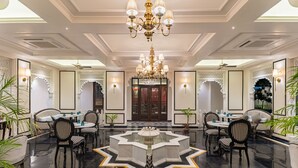 Un hall d’hôtel luxueux, agrémenté d’une fontaine centrale, de lustres élégants et d’une décoration de style traditionnel.