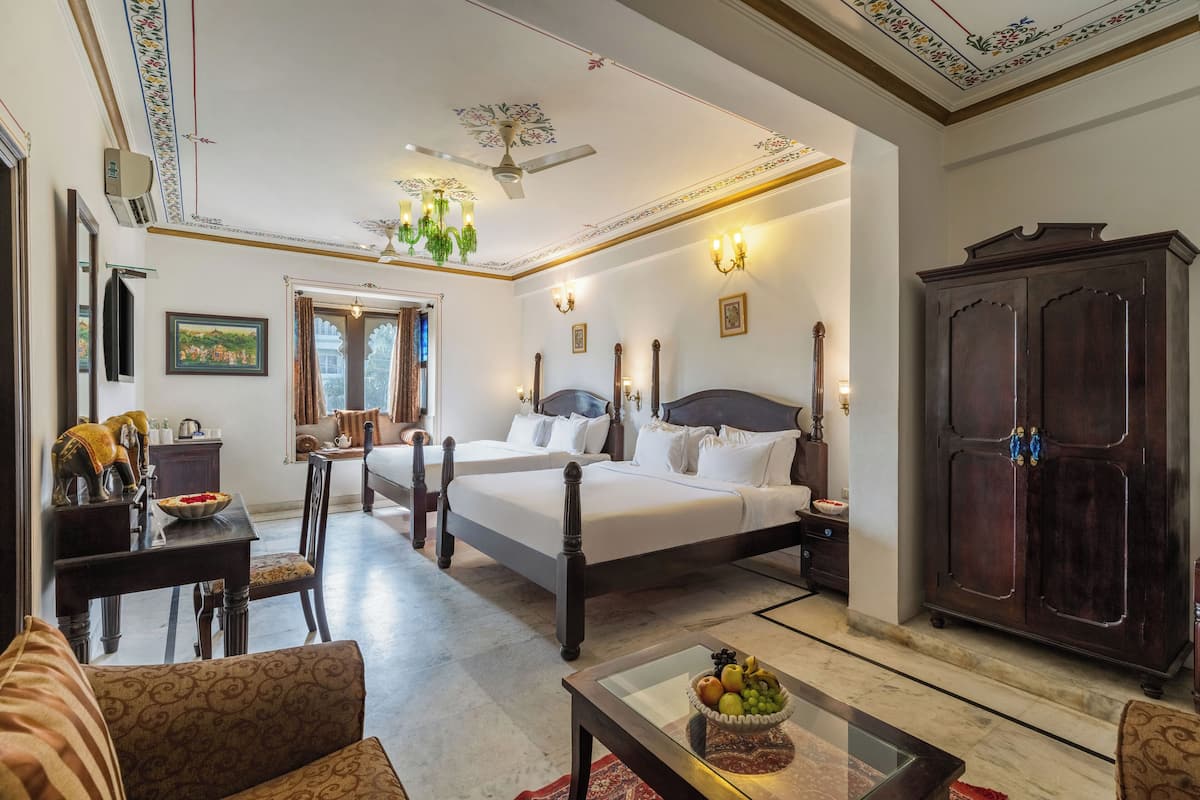 Een ruime slaapkamer met een groot bed, een houten garderobe, een zithoek met een tafel en stoelen, en een plafondventilator.