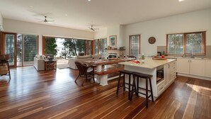 A spacious kitchen with a central island, large windows, and a view of the outdoors. - Tula - waterfront reserve (Currarong)