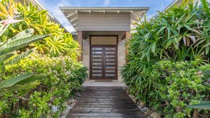 A house with a wooden deck leading to a double door, surrounded by lush tropical plants. - Tula - waterfront reserve (Currarong)