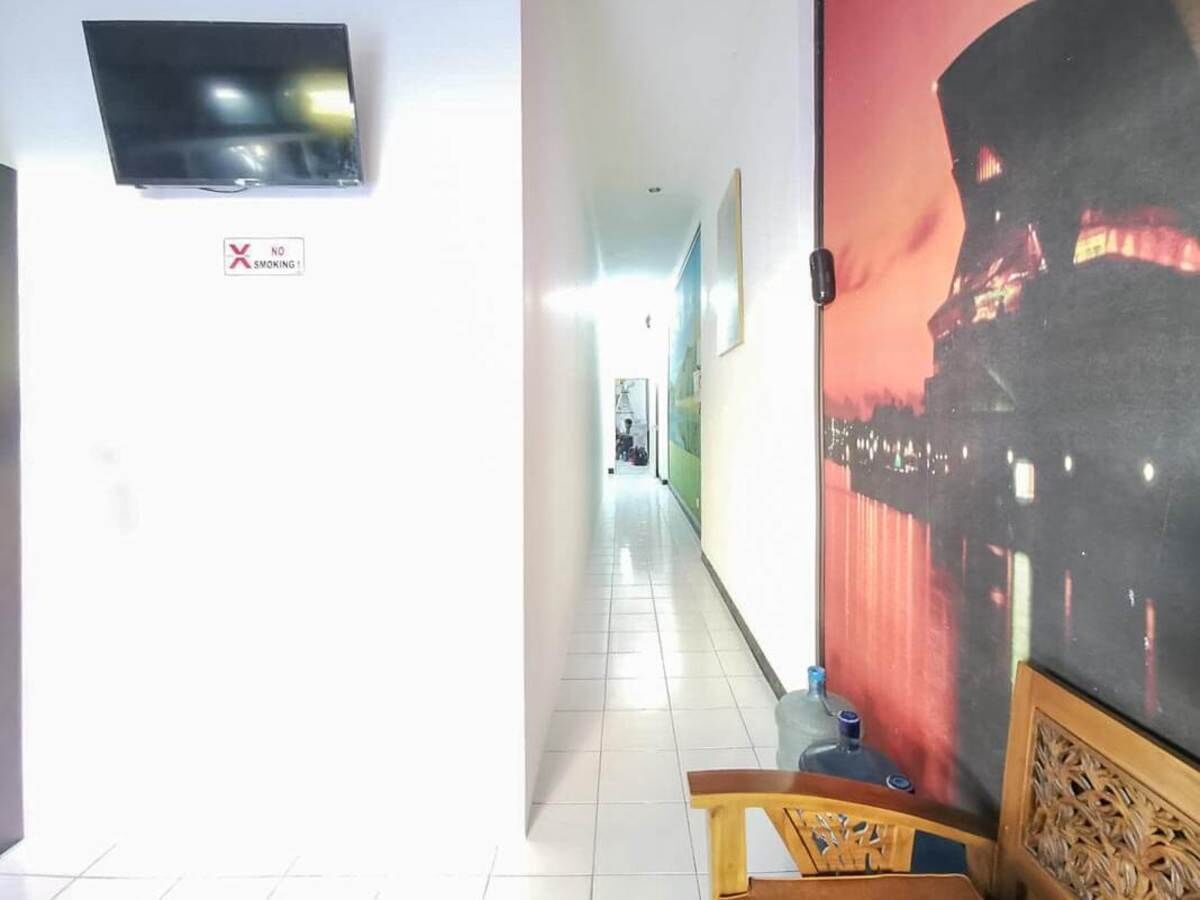 A hallway with a 'No Smoking' sign, a television mounted on the wall, and a large framed picture on the right.