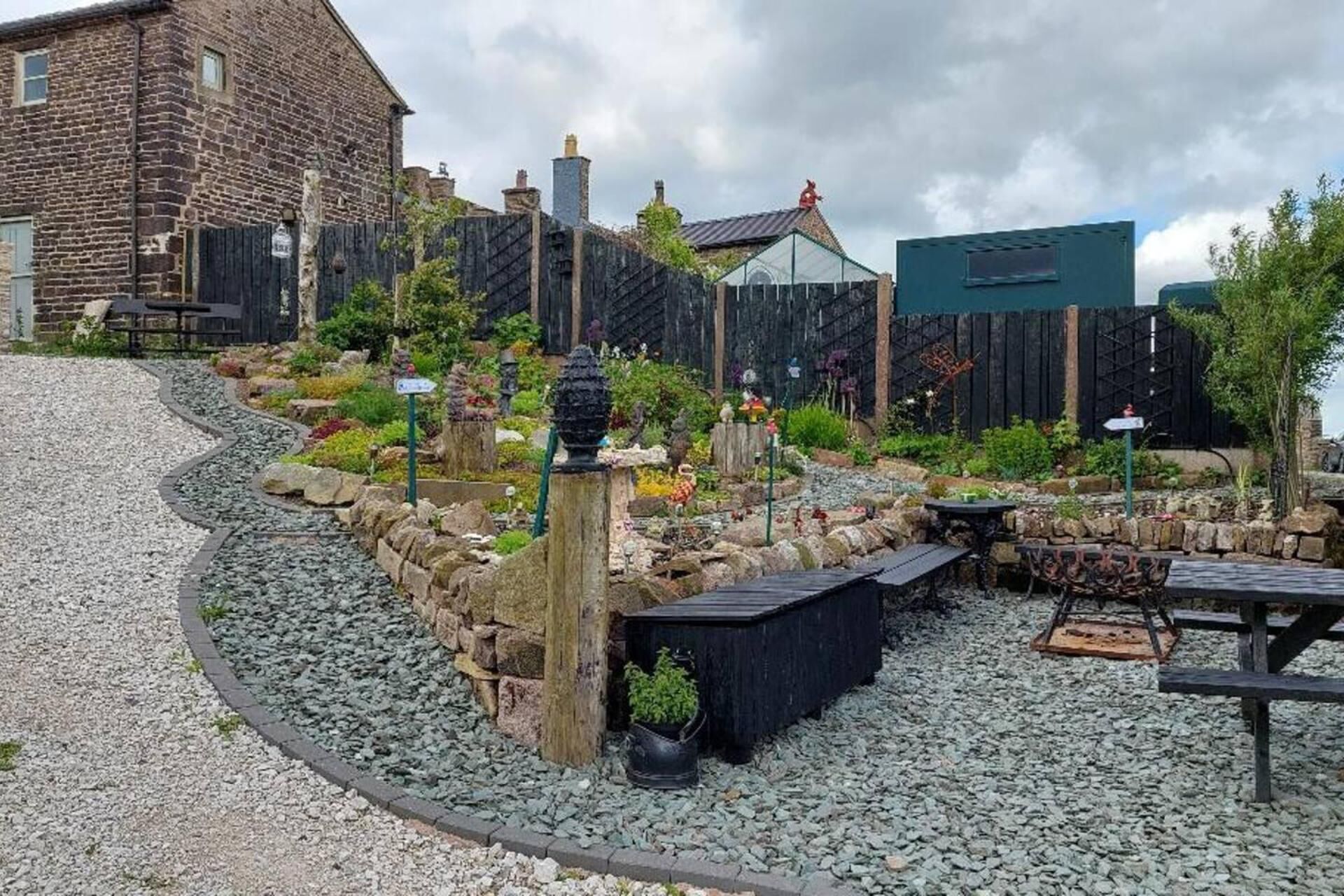 A garden with a stone wall, a wooden bench, and a metal table.