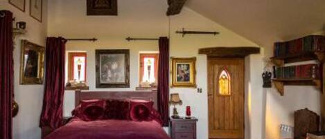 A bedroom with a large bed, a wooden door, and a bookshelf.