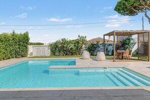A swimming pool with a pergola and outdoor seating area.
