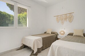 Une chambre avec deux lits, une fenêtre donnant sur la forêt et un élément décoratif fixé au mur.