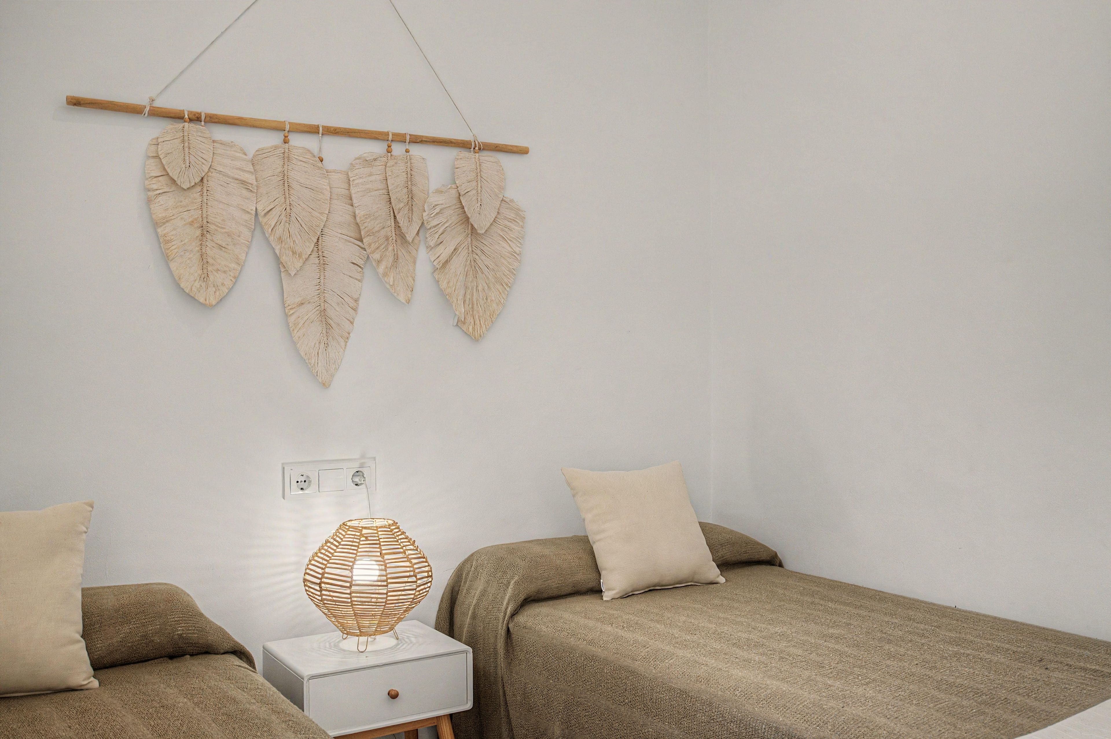 Quarto com duas camas, abajur e decoração nas paredes.
