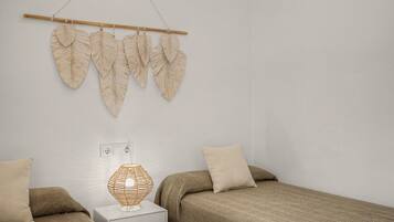 Quarto com duas camas, abajur e decoração nas paredes.
