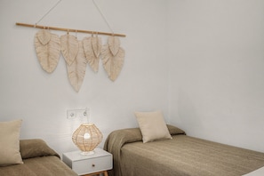 Un dormitorio con dos camas, una lámpara de noche y decoración en la pared.