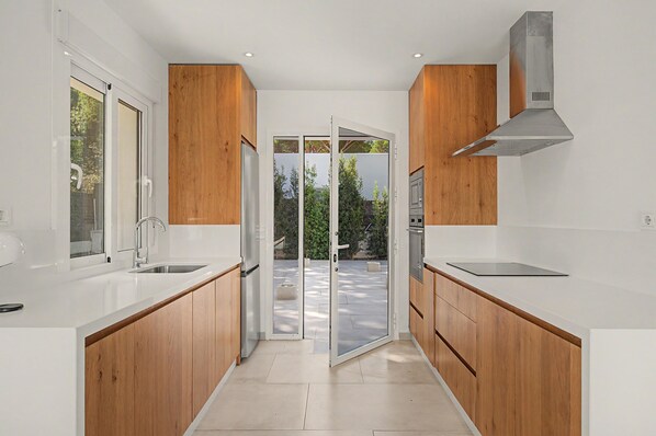 Une cuisine moderne avec des meubles en bois, un réfrigérateur en acier inoxydable et un four encastré.