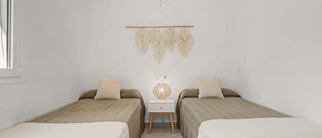 A room with two beds, a small table, and a wall-mounted decoration.