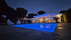 A modern house with a swimming pool, outdoor seating, and a well-lit patio area. - Casa Robert in Conil with Pool, Hot Tub, Garden, and Wi-Fi (Conil)