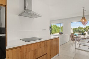 Une cuisine moderne dotée d’un grand îlot central, de meubles en bois et donnant sur un espace patio extérieur.