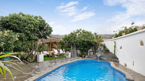 A swimming pool with a wooden deck, lounge chairs, and a pergola. - Vacation Home "Casa Candelaria" with Views of El Teide, Private Pool & Wi-Fi (Arico)