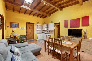 A spacious living area with a dining table, sofas, and a kitchen in the background.
