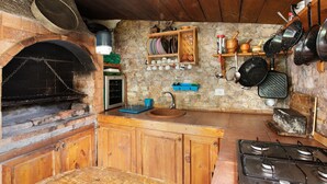 A rustic kitchen with a stone wall, wooden cabinets, a built-in oven, and a gas stove. - Vacation Home "Casa Candelaria" with Views of El Teide, Private Pool & Wi-Fi (Arico)