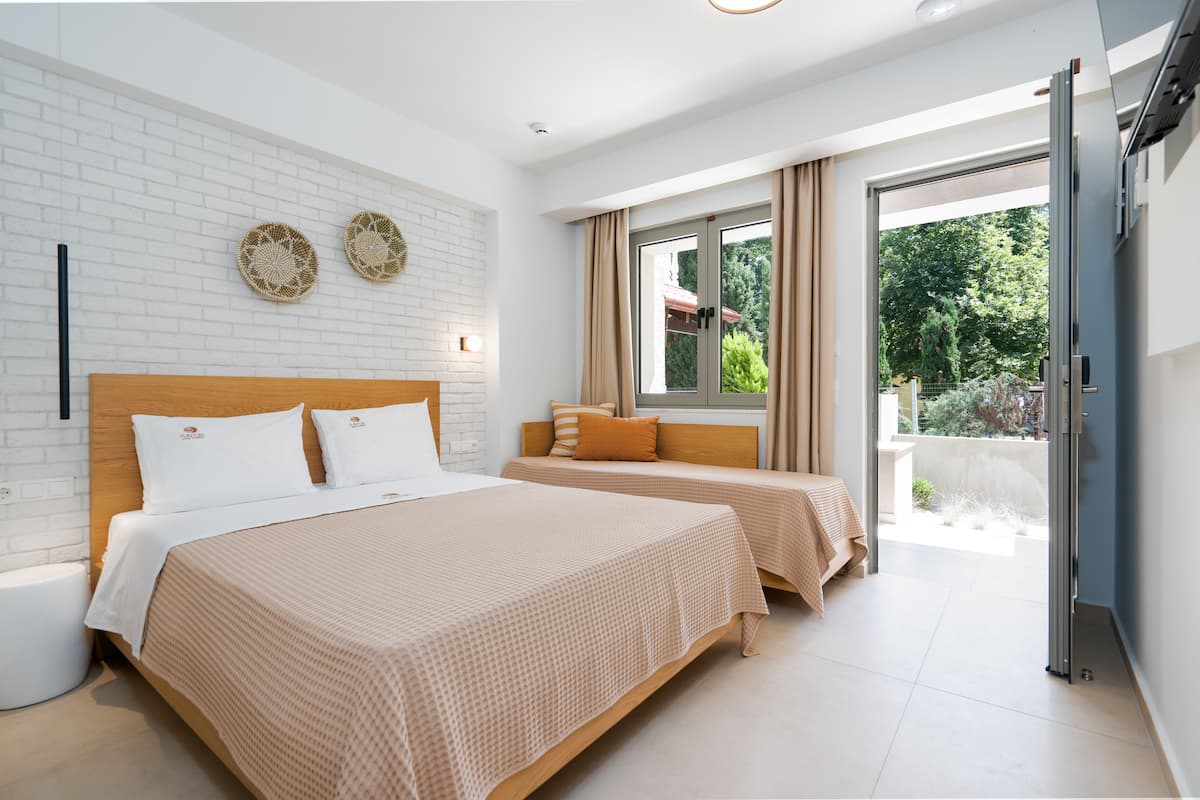 A modern hotel room with two beds, a white brick wall, and a balcony with curtains.