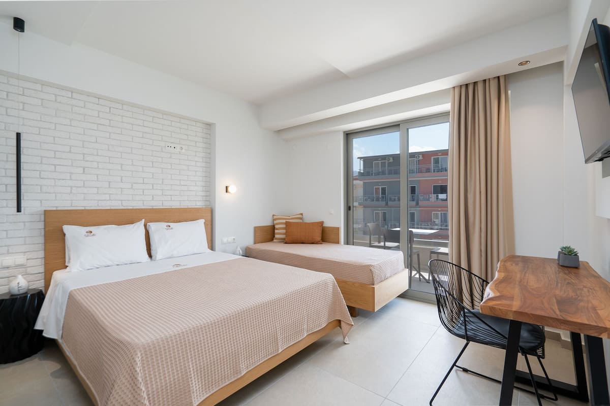 A hotel room with two beds, a wooden table, a chair, and a TV.