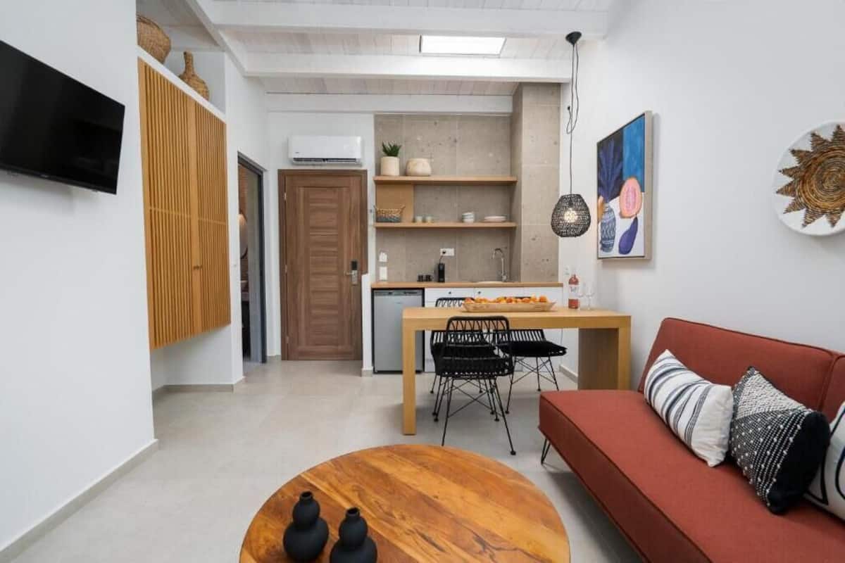 A modern living room with a red sofa, a wooden coffee table, and a dining area with a wooden table and chairs.