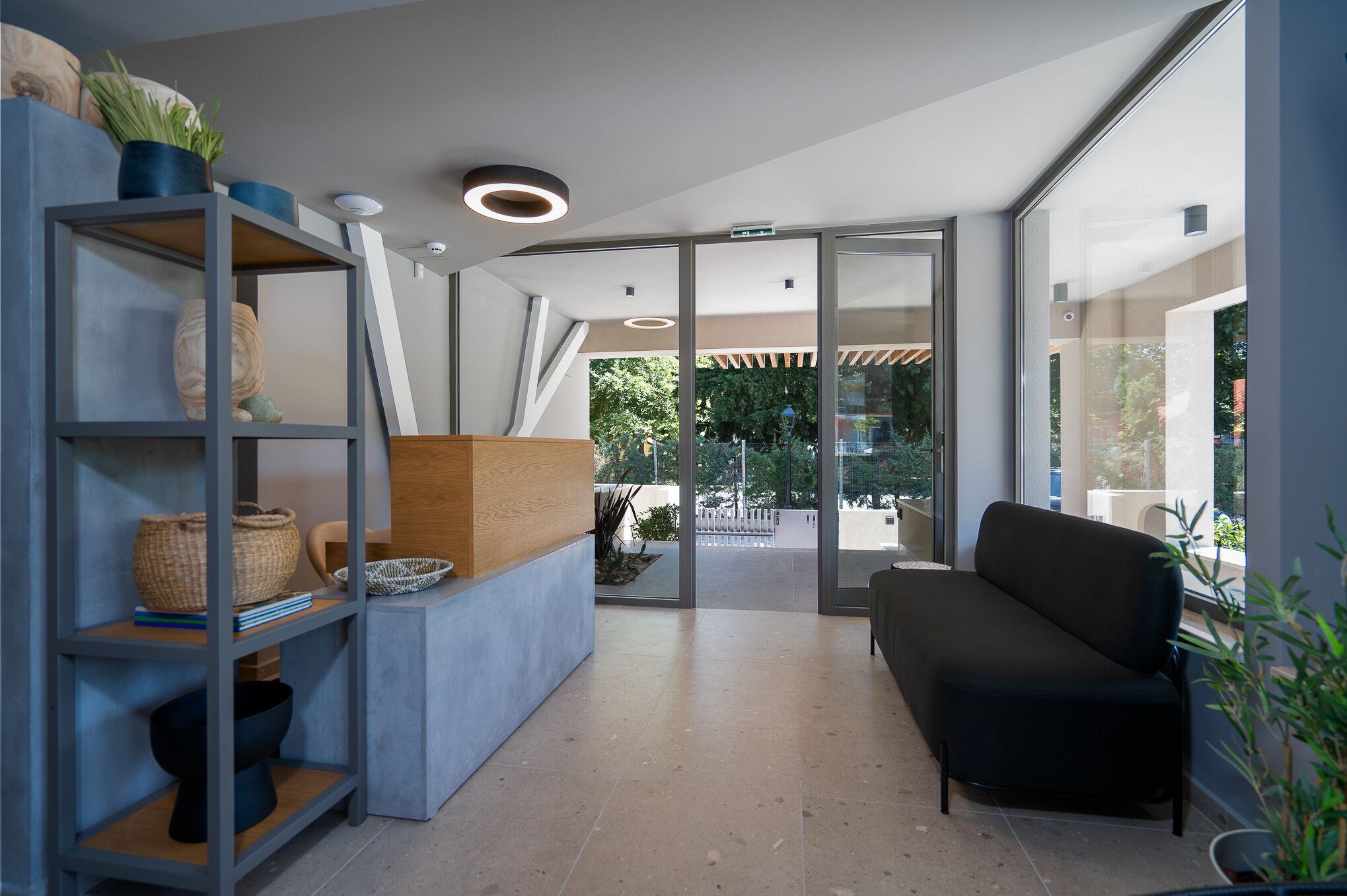 A modern interior with a sofa, shelves with decorative items, and a glass door leading outside.