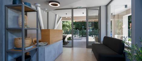 A modern interior with a sofa, shelves with decorative items, and a glass door leading outside.