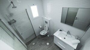 Baño pequeño con ducha, inodoro y lavamanos, que incluye un espejo y una ventana.