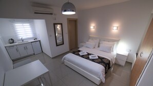 Un dormitorio con cama, mesitas de noche, un escritorio y un espejo.
