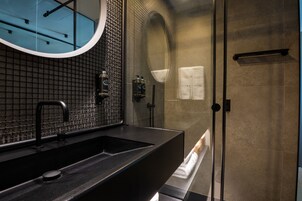 A modern bathroom with a black sink, a large mirror, and a glass-enclosed shower area.