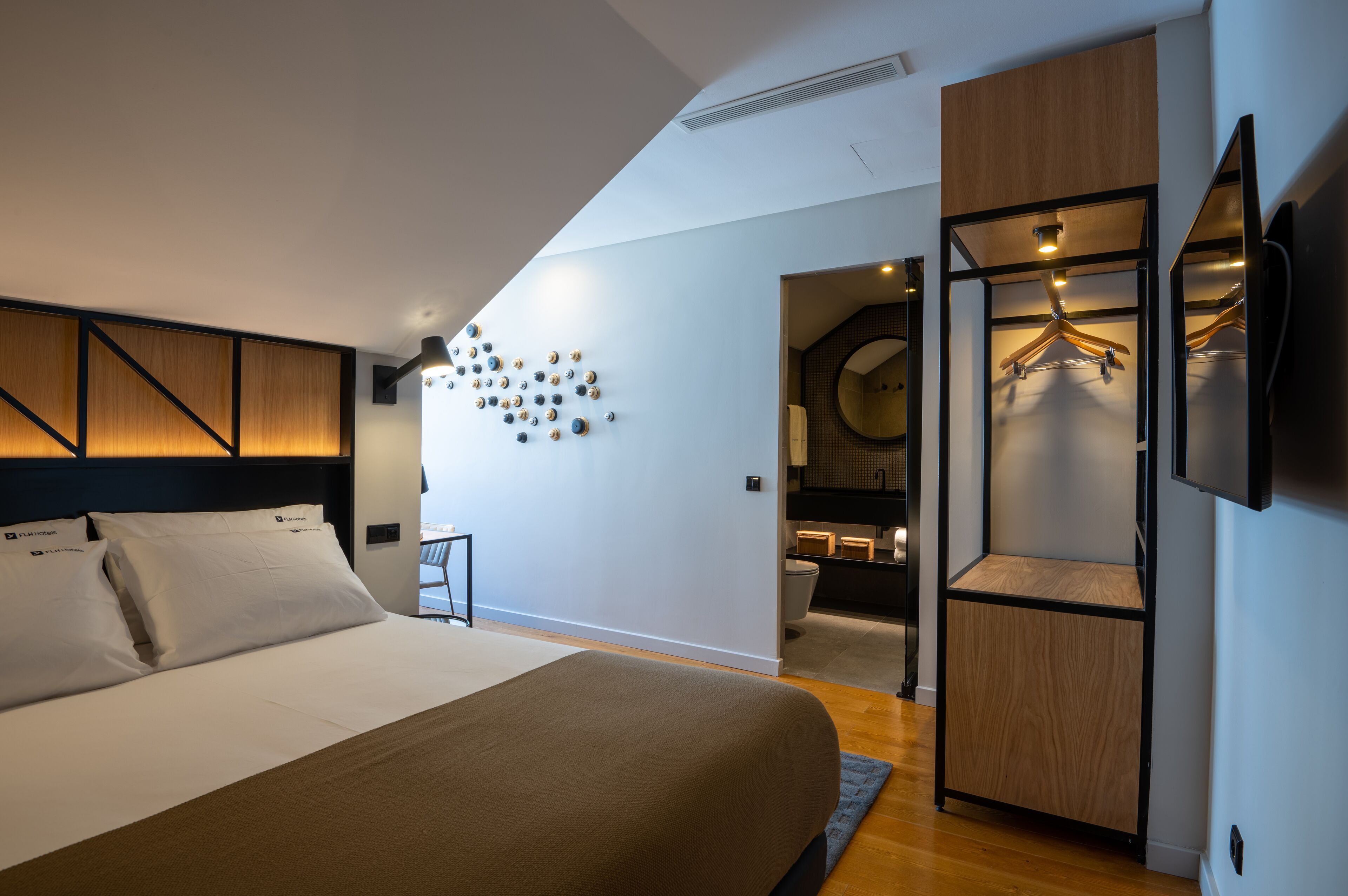 Un dormitorio moderno con una cama grande, un armario con espejo y un televisor montado en la pared.