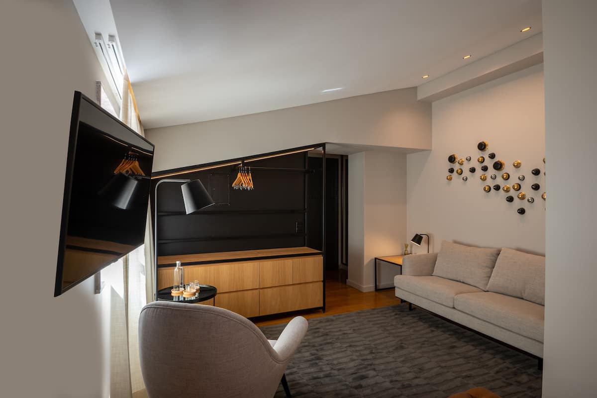 Una sala de estar moderna con un sofá, una mesa de centro, un televisor montado en la pared y una obra de arte decorativa.