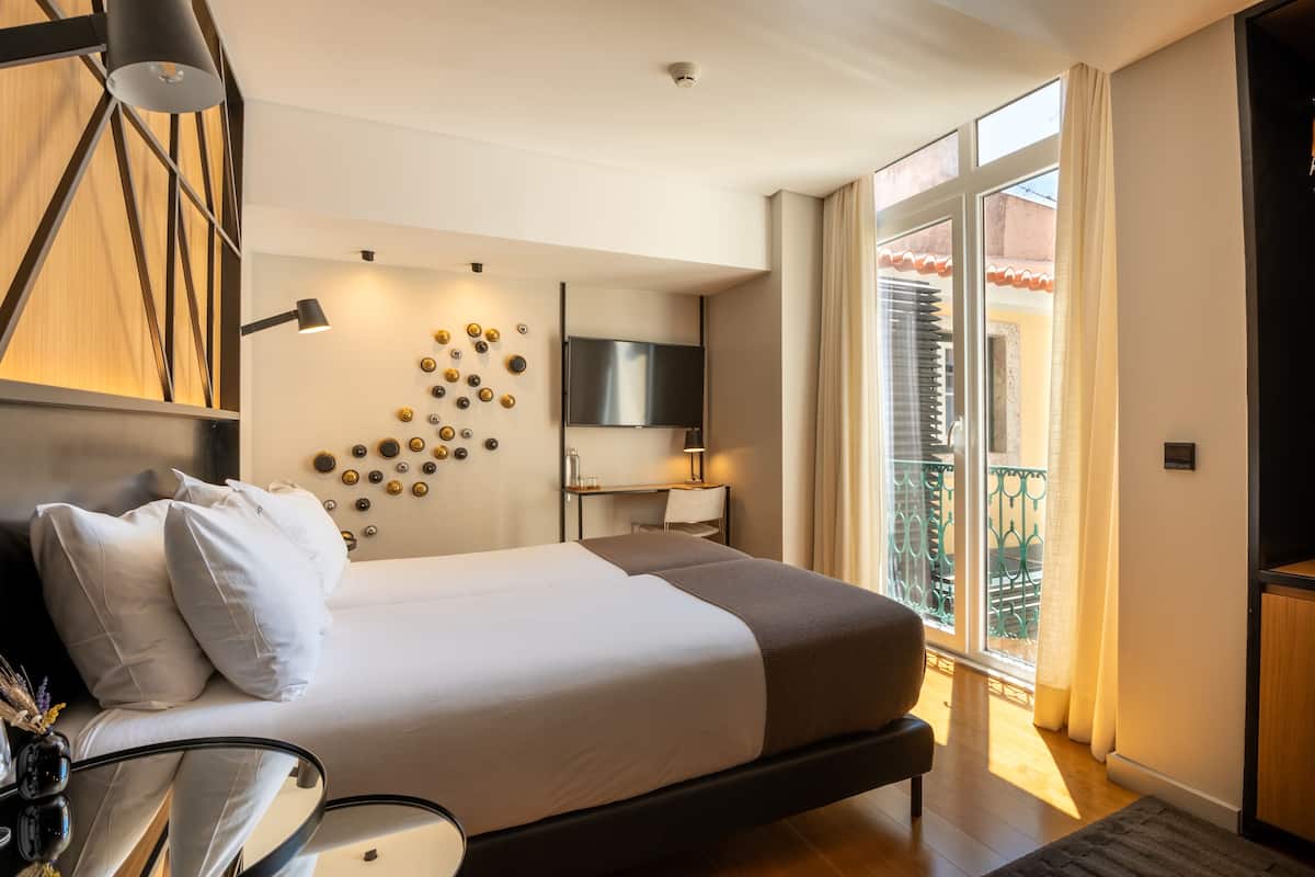 Habitación de hotel moderna con una cama grande, televisión, escritorio y balcón con vistas.