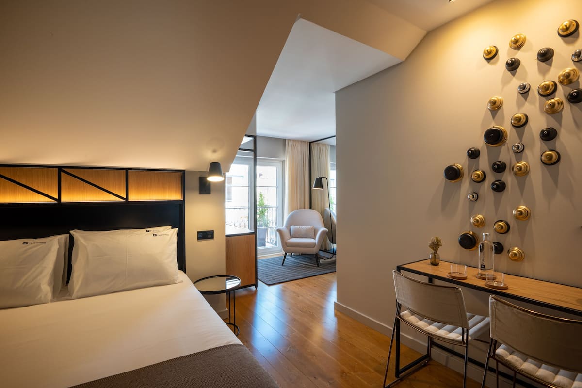 Habitación de hotel con cama, escritorio y sillas. Una pared decorada con platos y vistas al exterior.