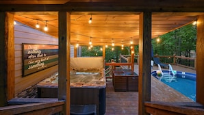 Eine Holzterrasse mit Whirlpool, Sitzgelegenheiten im Freien und einem Pool.