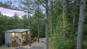 Eine moderne Hütte mit einer Terrasse, umgeben von dichtem Wald.
