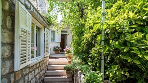 Un escalier en pierre mène à une maison avec des volets blancs et des plantes en pot.