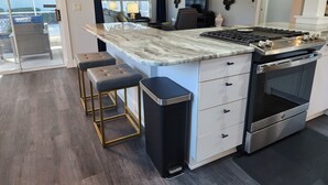 Eine moderne Küche mit Marmorarbeitsplatte, Edelstahlgeräten und einer Bar mit Hockern.
