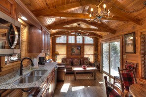 A wooden cabin interior with a kitchen, dining area, and seating space.