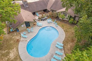 An aerial view of a residential area with a swimming pool, lounge chairs, and a barbecue area.