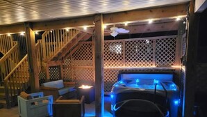 Een jacuzzi met blauwe LED-verlichting, een houten terras en een trap.