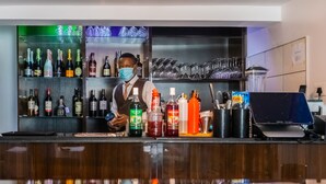 Een bar met een bartender, planken vol drankflessen en een digitaal betaalterminal.