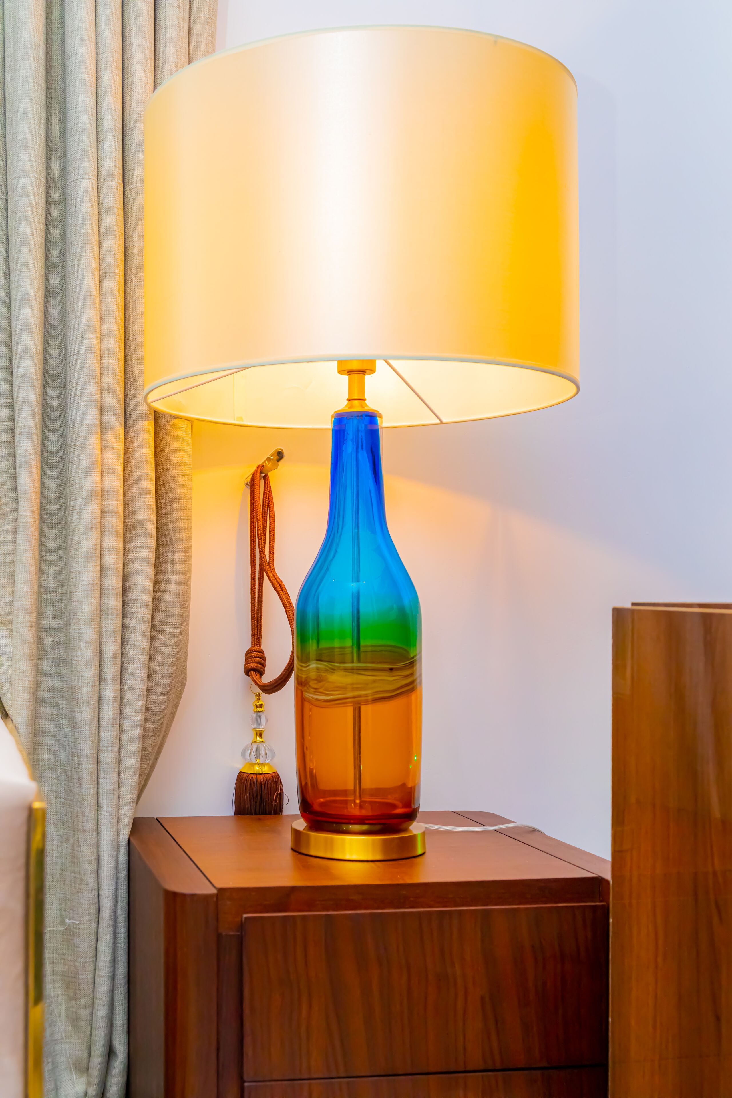 Une table de chevet en bois, avec une lampe bleue et un petit objet décoratif.