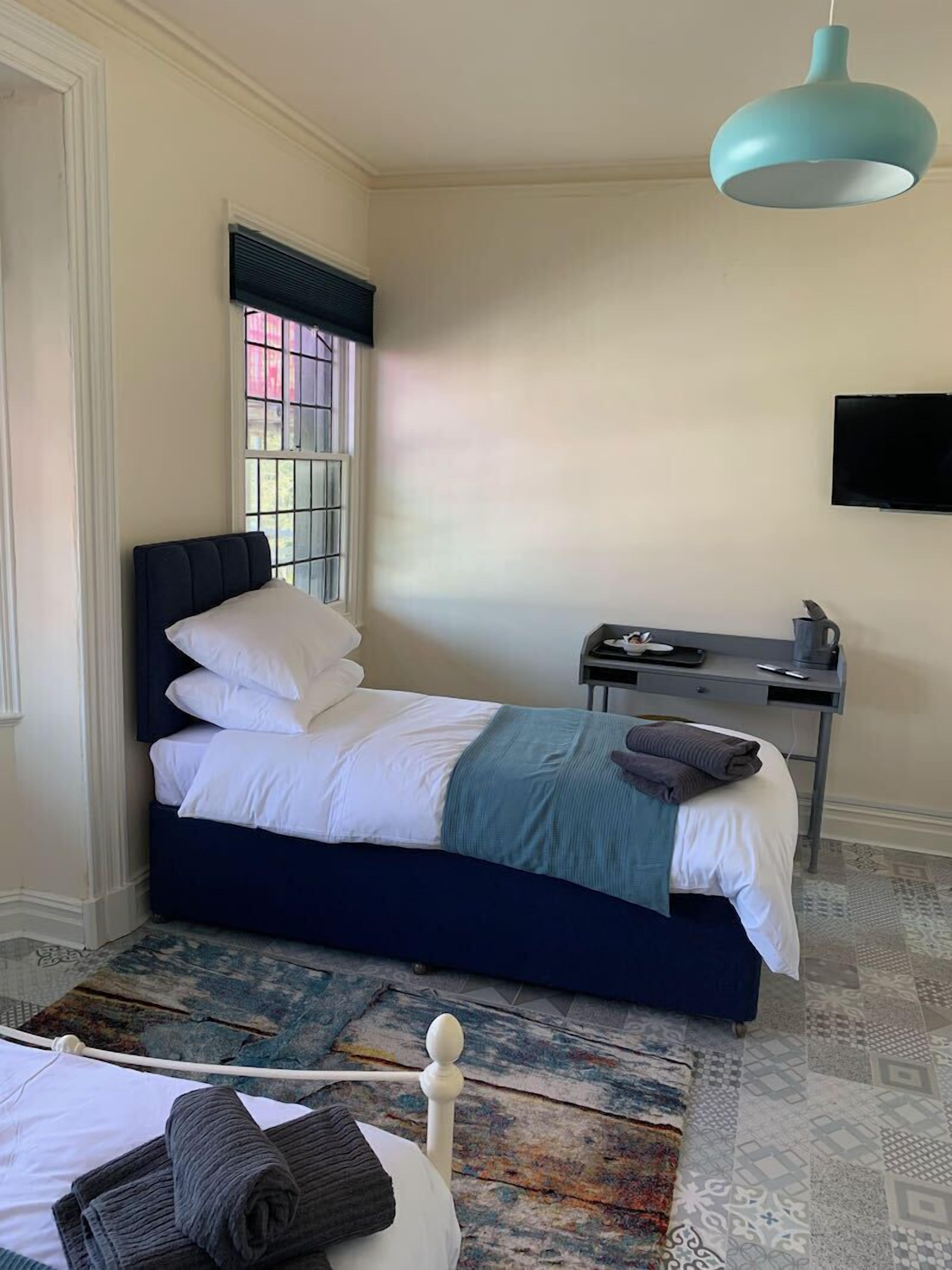 Siististi järjestetty makuuhuone, jossa on sänky, työpöytä ja televisio.